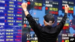 A man look at an electronic stock indicator of a securities firm in Tokyo, Wednesday, Sept. 9, 2015.