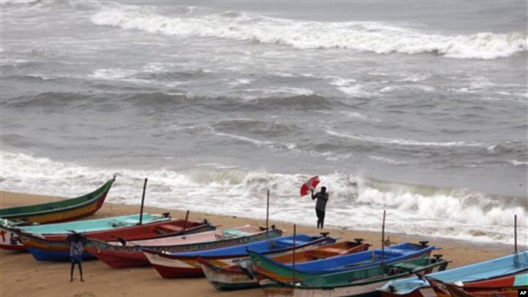 Seorang warga India berusaha memegang kuat payungnya saat angin kencang bertiup di kawasan pelabuhan Chennai, India selatan menjelang datangnya badai Nilam (30/10).
