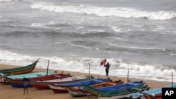 Seorang warga India berusaha memegang kuat payungnya saat angin kencang bertiup di kawasan pelabuhan Chennai, India selatan menjelang datangnya badai Nilam (30/10).