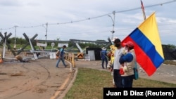 Seorang pria memegang bendera Kolumbia selama protes menuntut tindakan pemerintah untuk mengatasi kemiskinan, kekerasan polisi dan ketidaksetaraan dalam sistem kesehatan dan pendidikan, di Cali, Kolombia, 10 Mei 2021. (Foto: REUTERS/Juan B Diaz)