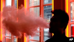 FILE - In this Feb. 20, 2014 file photo, a customer exhales vapor from an e-cigarette at a store in New York. On Friday, Aug. 30, 2019, the Centers for Disease Control and Prevention said they are investigating more cases of a breathing illness associated with vaping.