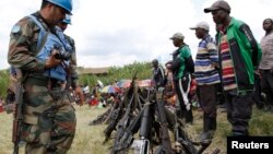 ARCHIVES - Des ex-combattants de groupes armés et milices déposent leurs armes aux pieds de casques bleus de la Mission des Nations unies en RDC, le 30 mai 2014.