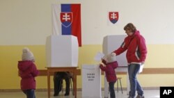 A child puts a vote in a ballot box during a general election in Bratislava, Slovakia, Saturday, March 10, 2012. 