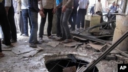 Syrians gather near a crater from a tank shell in a neighborhood of the capital, Damascus, after a raid by Syrian troops killed several rebels and civilians, April 5, 2012. 