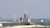 Space shuttle Endeavour (center) is on launch Pad 39A midday after a scrubbed launch attempt. On the left is Launch Pad 39B, surrounded by lightning towers, which will be used for the Constellation Program.