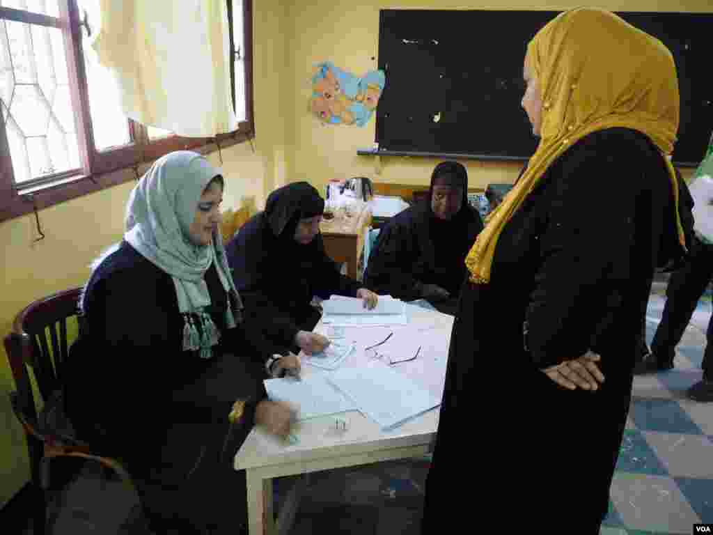 Egyptian women search for a name on a voting list at a polling station in Cairo, Egypt, Dec. 1, 2015. (Photo - H. Elrasam/VOA)