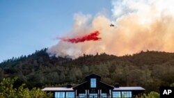 Pesawat menjatuhkan bahan kimia untuk mengatasi kebakaran hutan di Calistoga, California, 27 September 2020.