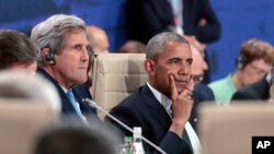 President Barack Obama waits next to State Secretary John Kerry for the start of the first working session of the North Atlantic Council at the NATO summit in Warsaw, Poland, Friday, July 8, 2016. 