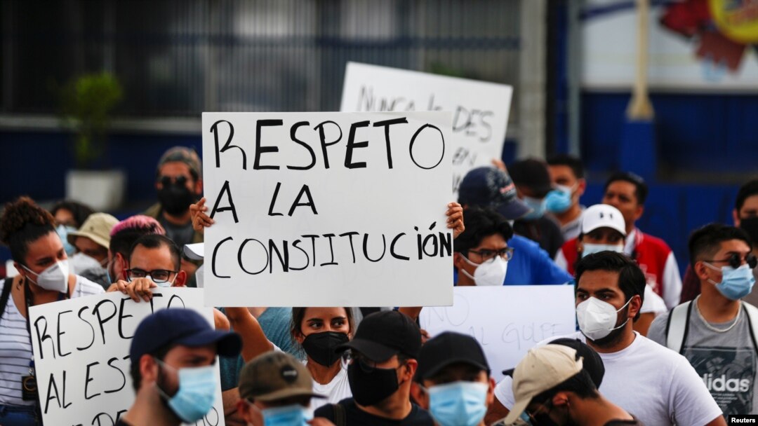 People hold signs reading "Respect the constitution," as they protest against the removal of Supreme Court judges and the Attorney General by El Salvador's congress, in San Salvador, May 2, 2021. 