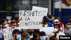People hold signs reading "Respect the constitution," as they protest against the removal of Supreme Court judges and the Attorney General by El Salvador's congress, in San Salvador, May 2, 2021. 