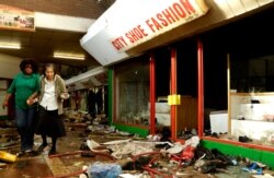 The owner of a shoe shop is helped by a staff member to inspect the damage caused by looters in Germiston, east of Johannesburg, South Africa, Sept. 3, 2019.