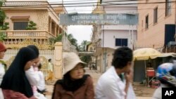 Cambodians and Muslims ride on a motor-cart past a catholic church in Phnom Penh, Cambodia, Tuesday, July 17, 2007. 