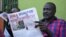 FILE - A man reads a copy of the Juba Monitor, with a heading referring to the killing of South Sudanese journalist Peter Moi of The New Nation newspaper, on August 21, 2015 in Juba.