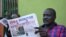 FILE - South Sudan's lawmaker Nhial Bol reads a copy of the Juba Monitor with a heading referring to the killing of South Sudanese journalist Peter Moi of The New Nation newspaper in Juba, Aug. 21, 2015 