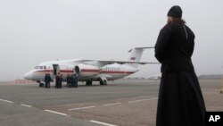 Un sacerdote ortodoxo observa un avión que lleva cadáveres de las víctimas de la caida del avión de Metrojet en Egipto.