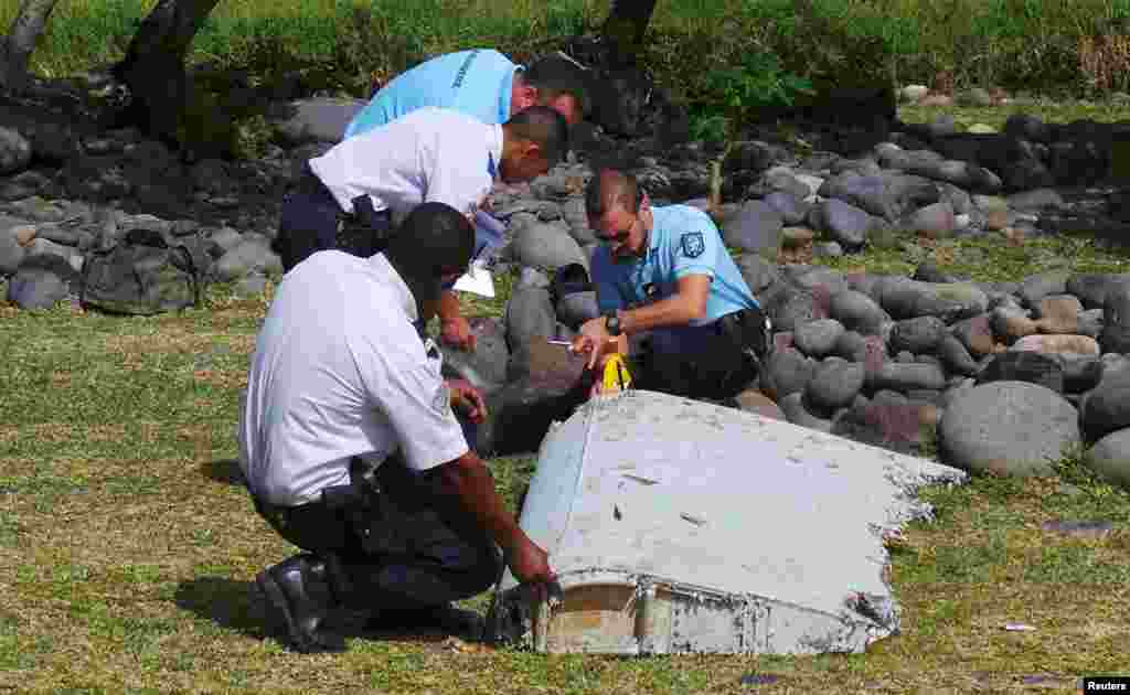 Des gendarmes et policiers français inspectent un morceau d&#39;avion trouvé sur la plage de Saint-André, sur l&#39;île de la Réunion, 29 juillet 2015.