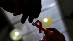 FILE - A nurse (L) hands out a red ribbon to a woman to mark World Aids Day at the entrance of Emilio Ribas Hospital, in Sao Paulo December 1, 2014. 