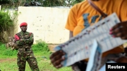 FILE - A military police member looks on, as an election worker counts ballots at a polling station, after polls closed, on the day of the national election, in Freetown, Sierra Leone, June 24, 2023.