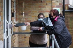 Volunteers hand out the COVID-19 home test kits to residents, in Goldsworth and St Johns, amid the outbreak of COVID-19 in Woking, Britain, Feb. 2, 2021.