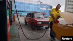 Un taxista abastece se abastece de combustible en una gasolinera en La Habana este 11 de diciembre, aunque el precio en bajo en comparación con otros países, los cubanos tienen dificultades para comprar el combustible.