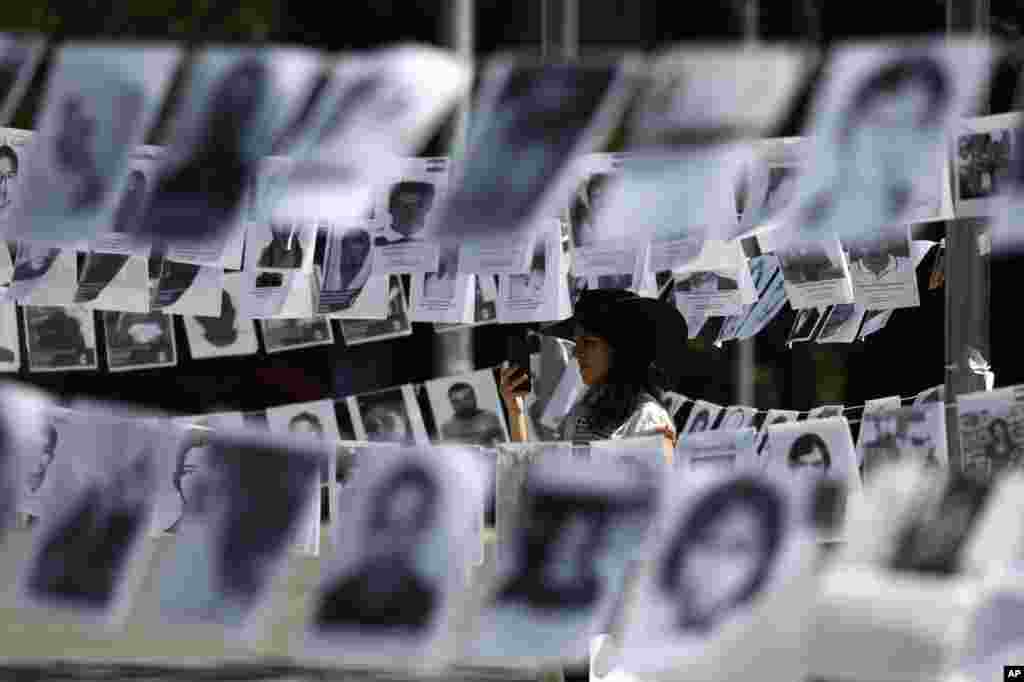 Surrounded by images of people who have disappeared, a woman takes pictures during a Mother&#39;s Day march in Mexico City, Mexico.