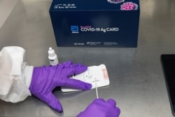 A healthcare professional adds the extraction reagent and a patient specimen to Abbott’s BinaxNOW COVID-19 Ag rapid test card, Sep. 2020.