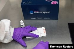 A healthcare professional adds the extraction reagent and a patient specimen to Abbott’s BinaxNOW COVID-19 Ag rapid test card, Sep. 2020.