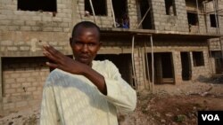 Prince Bala outside the half-finished construction where the IDPs are lodging. (VOA / K. Hoije)