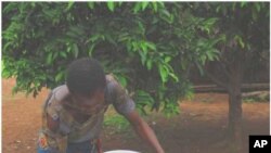 FILE - A Nigerian teen demonstrates one technique for filtering water to remove water fleas that carry Guinea worm larva in this 2005 file photo.