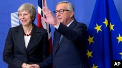 El presidente de la Comisión Europea, Jean-Claude Juncker (D), saluda a la primera ministra británica Theresa May en la sede de la UE en Bruselas, el miércoles 21 de noviembre de 2018.