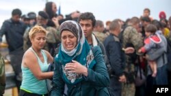 A migrant cries as she tries to break through the cordon of Macedonian police forces, while waiting to board a bus after crossing the Macedonian-Greek border near Gevgelija on Sept. 10, 2015. 