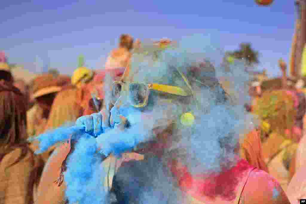 Seorang perempuan meniup bubuk cat warna biru ke arah rekannya dalam Festival warna Holi One di Cape Town, Afrika Selatan.