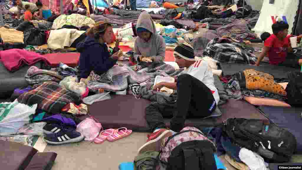 Los migrantes de Centro América se encuentran en un alburgue en Tijuana. En esta imagen se aprecia personas compartiendo alimentos en el piso.&nbsp; Fotografía: Celia Mendoza- VOA