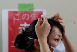 Seorang pekerja medis mencoba melepas masker pelindung wajah di bangsal ICU untuk pasien COVID-19 di Rumah Sakit Universitas Kedokteran St.Marianna di Kawasaki, selatan Tokyo, Jepang, 4 Mei 2020. (Foto: REUTERS / Issei Kato)