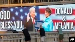 Papan reklame bergambar Presiden Donald Trump dan ibu negara Melania Trump, di dekat jembatan di Tel Aviv, Israel, Sabtu, 3 Oktober 2020. (AP Photo / Oded Balilty)