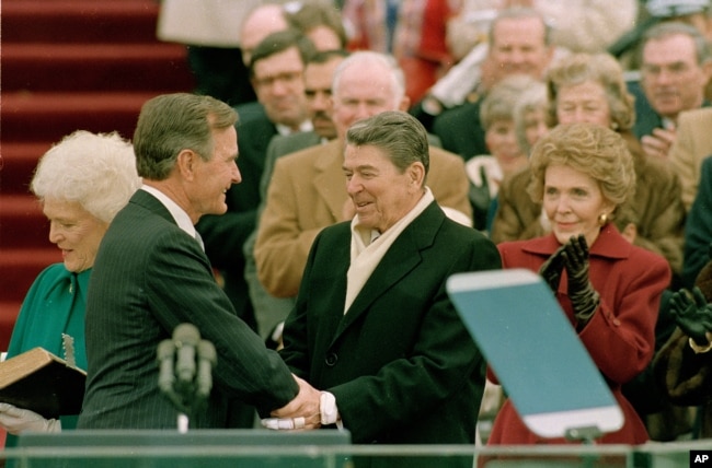 FILE - In this Jan. 20, 1989, photo, President George H.W. Bush, left, is congratulated by outgoing President Ronald Reagan after Bush took the oath of office as the 41st president of the United States on Capitol Hill in Washington.