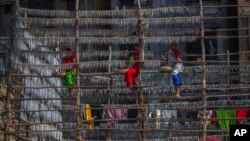 Fisherwomen hang fish on a structure made of bamboo poles to sun-dry them at a fishing colony in Mumbai, India.