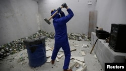 A customer wearing protective gear smashes old furniture with a hammer in an anger room in Beijing, China January 12, 2019. Picture taken January 12, 2019. 