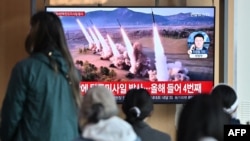 People watch a television screen showing a news broadcast with file footage of a North Korean missile test, at a railway station in Seoul on April 22, 2024.
