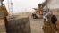 This image from video posted by Iraqi Revolution, a group supporting ISIL, shows a militant standing in front of a burning Iraqi Army Humvee in Tikrit, Iraq, June 11, 2014.
