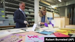 Jan Ramirez, chief curator at the 9/11 Memorial & Museum, right, sifts through a collection of condolence cards for a victim of 9/11 that were donated to the museum's archive, July 16, 2021, in Jersey City, New Jersey. (AP Photo/Robert Bumsted)