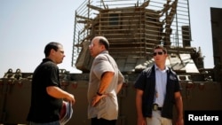 Israeli Defense Minister Moshe Yaalon (C) stands in front of an armored personnel carrier (APC) during a visit to a military base near Kibbutz Kissufim outside the central Gaza Strip, May 7, 2013.