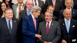 El secretario de Estado, John Kerry, conversa con el canciller jordano, Nasser Juden, mientras preparan la pose para la foto de la Conferencia de Donantes para Gaza.