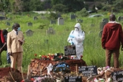 A preacher speaks to a health worker during a burial of a person who died from COVID-19, in Harare, Zimbabwe, Jan, 15, 2021.