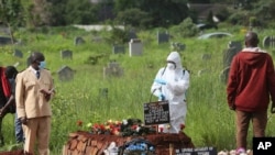 A preacher speaks to a health worker during a burial of a person who died from COVID-19, in Harare, Zimbabwe, Jan, 15, 2021.