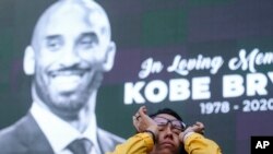 Nicole Mascarenhas, wipes her eyes in front of a screen with the late Kobe Bryant at a memorial for Kobe Bryant near Staples Center, Jan. 27, 2020, in Los Angeles. 