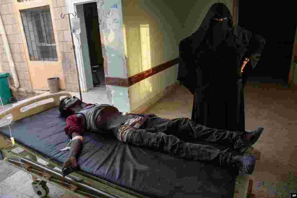 An Ethiopian Tigray migrant who was imprisoned by traffickers for months, lies on a gurney accompanied by a nurse at the Ras al-Ara Hospital in Lahj, Yemen, Aug. 1, 2019. Nurses gave him fluids but he died several hours later.