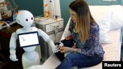 FILE - New recruit "Pepper" the robot, a humanoid robot designed to welcome and take care of visitors and patients, holds the hand of a new born baby next to his mother at AZ Damiaan hospital in Ostend, Belgium June 16, 2016. (REUTERS/Francois Lenoir)