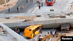 Rescue workers try to reach vehicles trapped underneath an overpass bridge that collapsed while under construction in Belo Horizonte, Brazil, July 3, 2014.