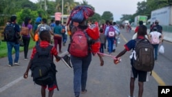 Numerosos migrantes de Centroamérica, África y el Caribe caminan en contingente por una carretera rumbo a Huixtla, tras partir de Tapachula, estado de Chiapas, en México, el sábado 12 de octubre, con vistas a llegar a la fronteras con Estados Unidos. AP